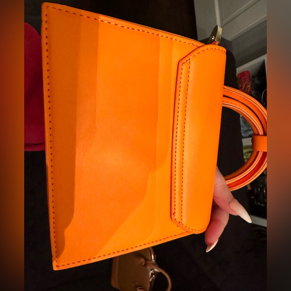 New. Orange loop top handle with longer strap. Gold hardware